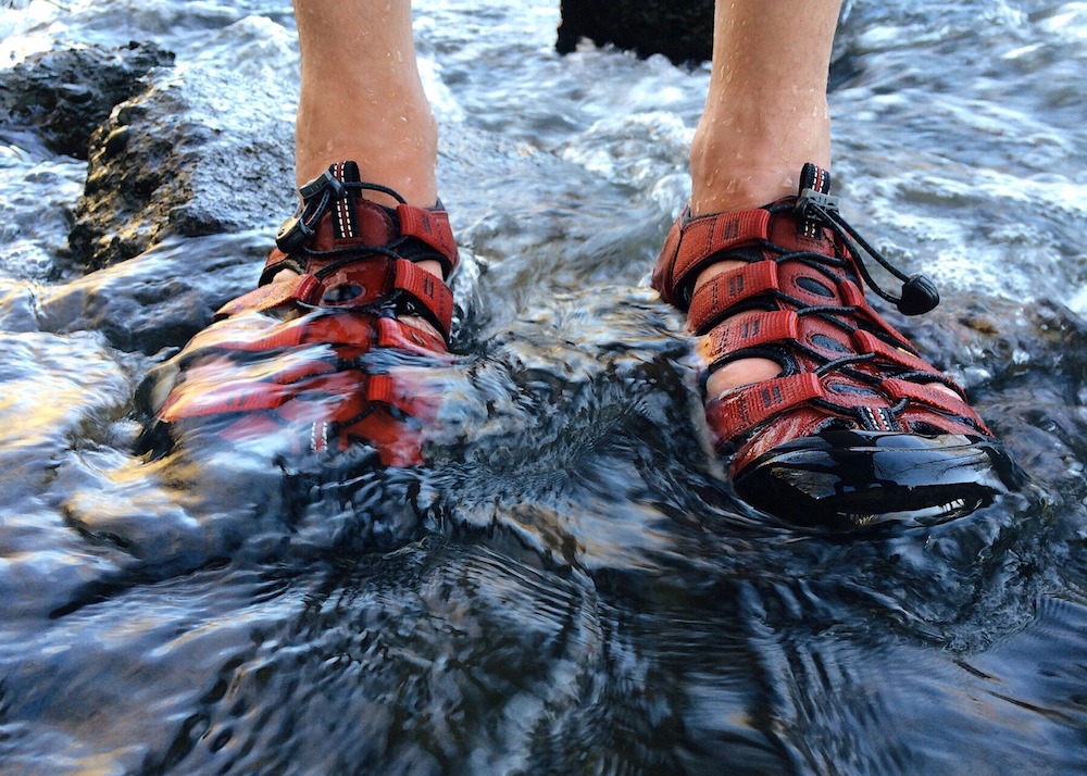 Men’s red hiking sandals in water.