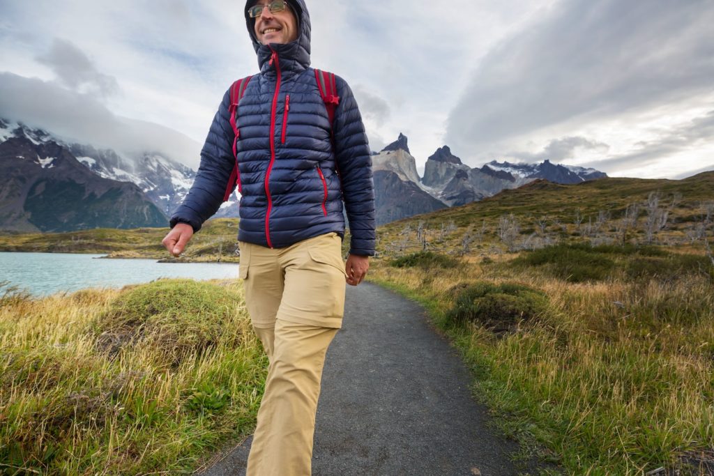 Man wearing a hooded jacket with mountains in the background