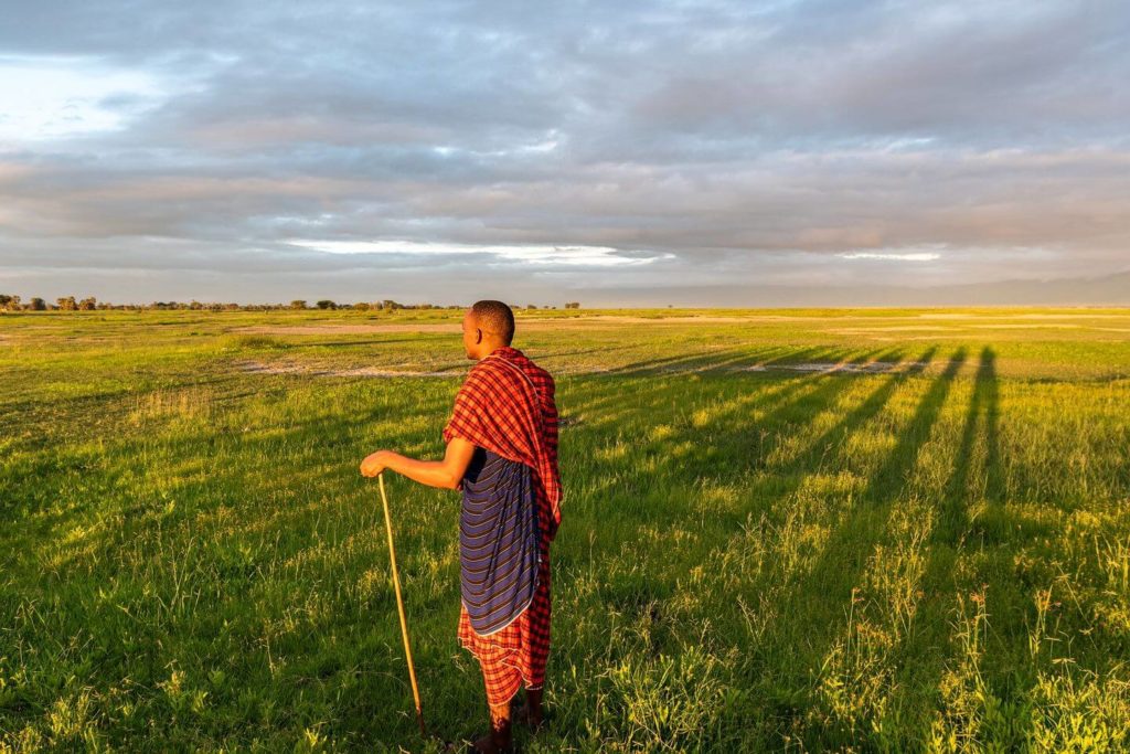 Masaai tribesman in traditional dress in grasslands Tanzania
