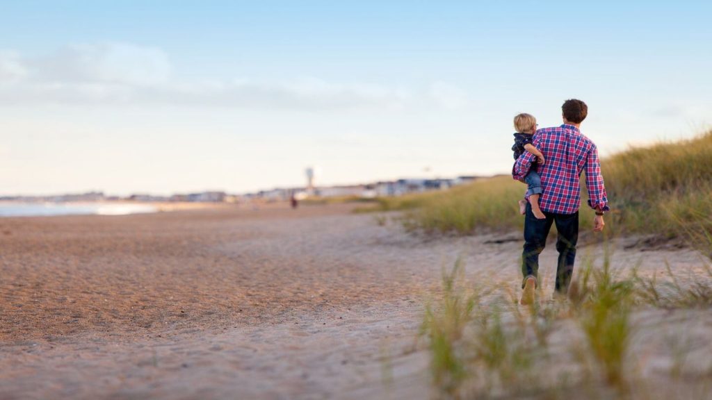 man holding his baby on the beach