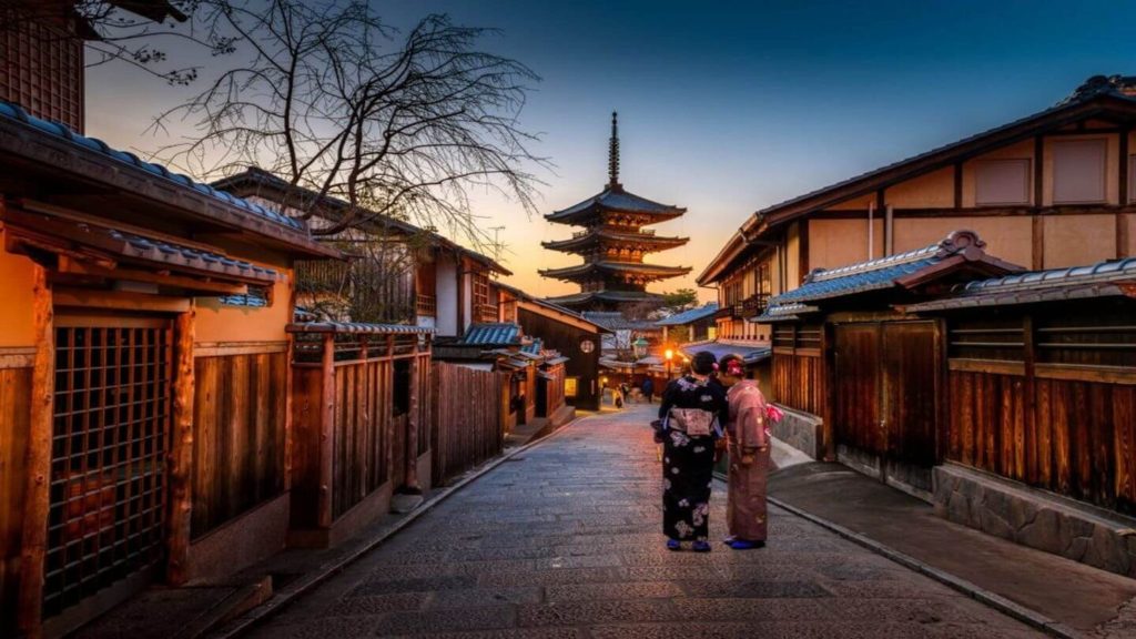 two women in kimonos in a traditional Japanese town at sunset