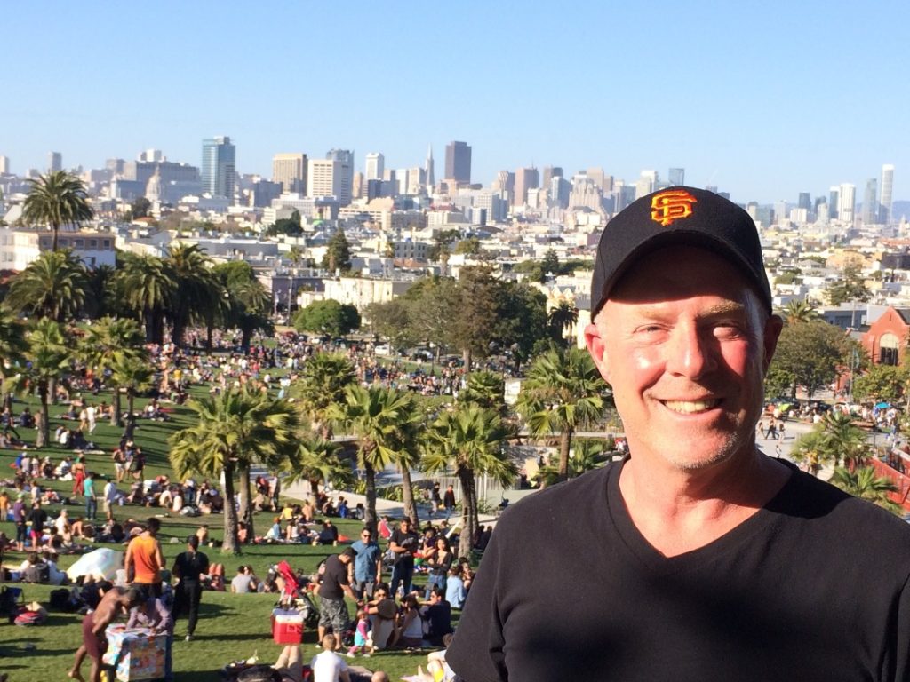 Stephen McNally in a US park, surrounded by people picnicking and palm trees