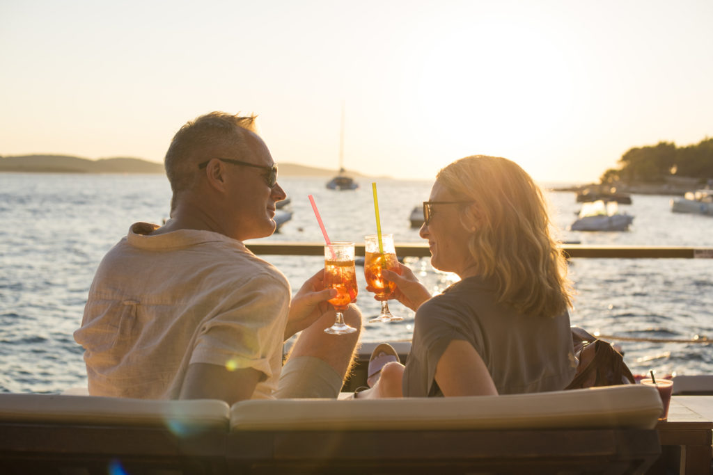 couple on holiday sharing a cocktail overlooking the water