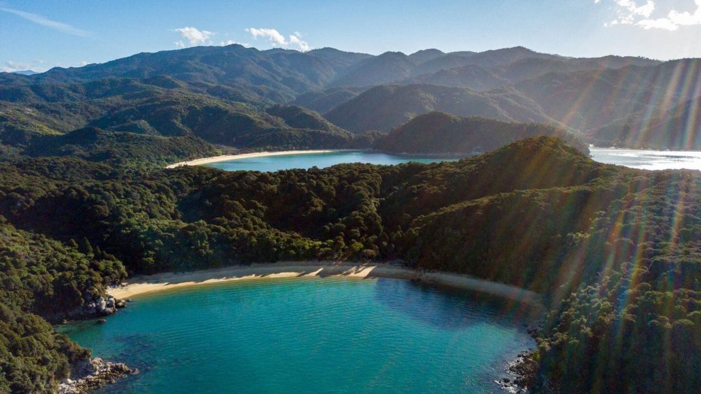 forests and mountains surrounded blue water bays and sandy beaches Abel Tasman New Zealand