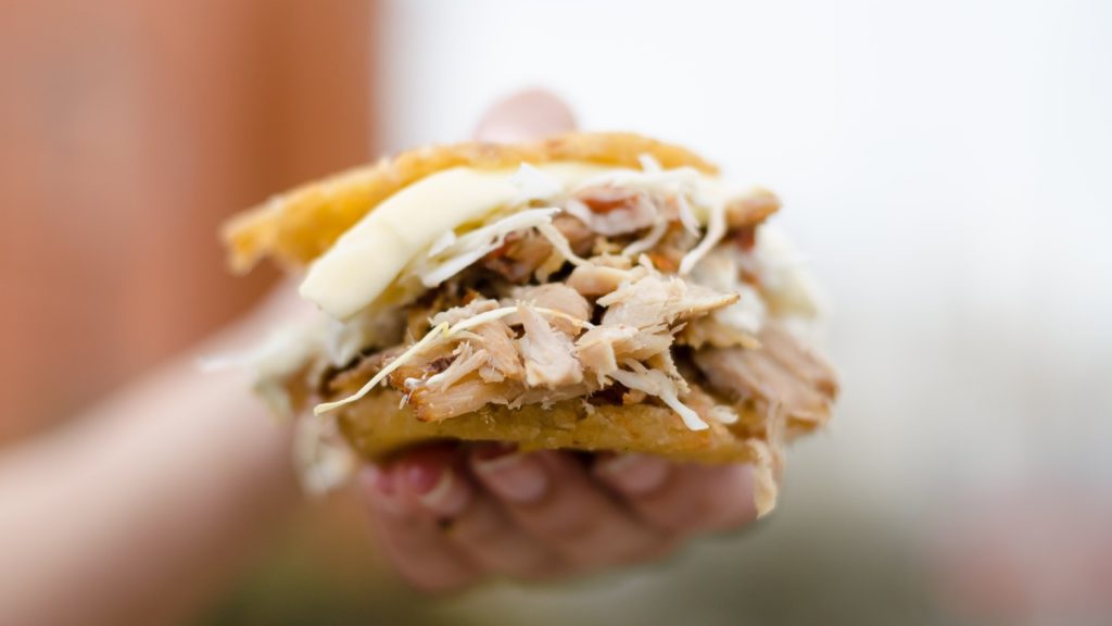 Person holding an Arepa, one of the best South American foods