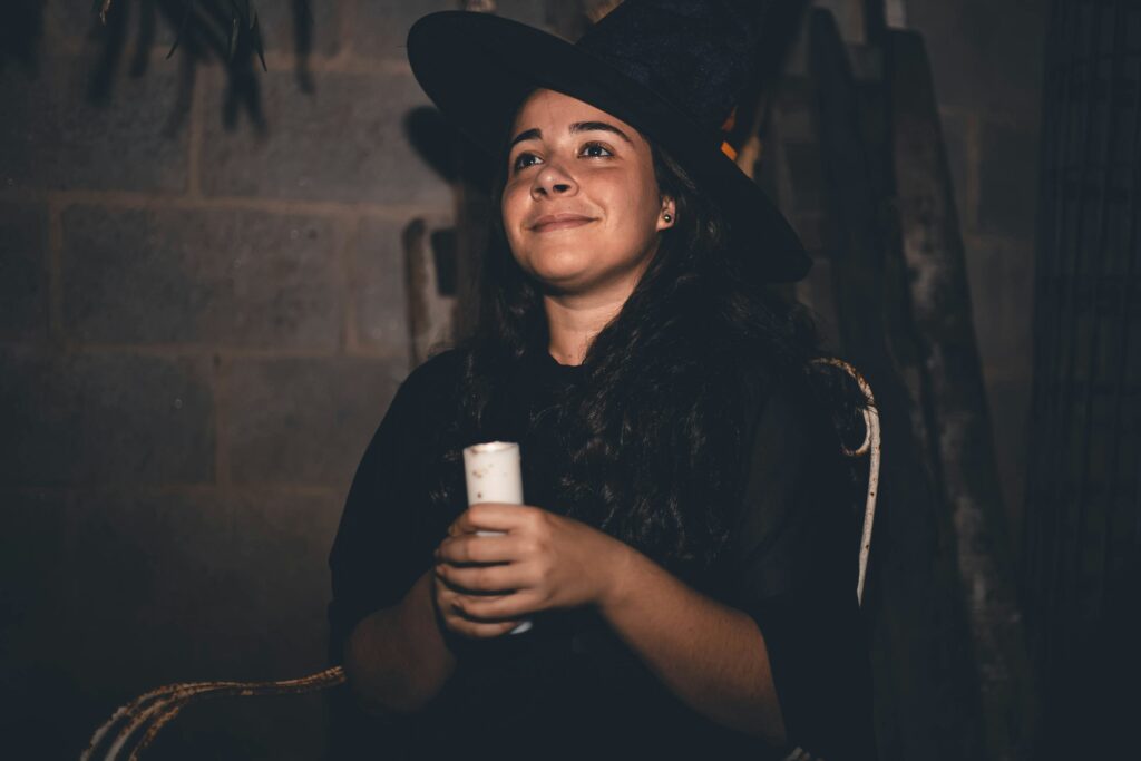 A woman dressed as a witch holding a candle in Lisbon, Portugal.