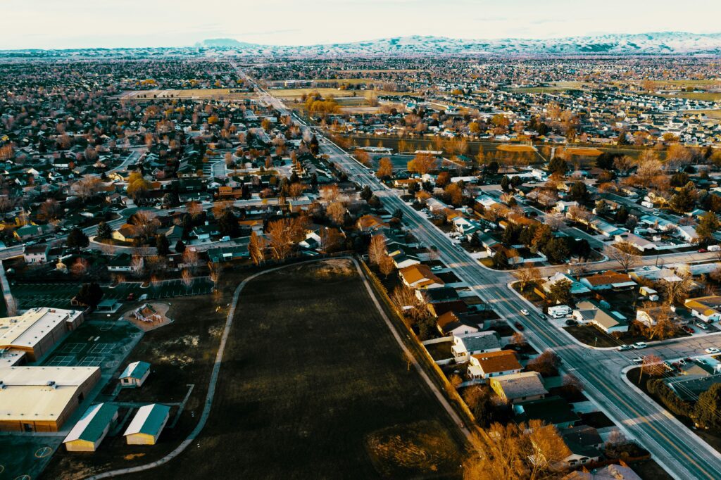The main roadway through Meridian, Idaho, flanked by orange trees and single-family homes.