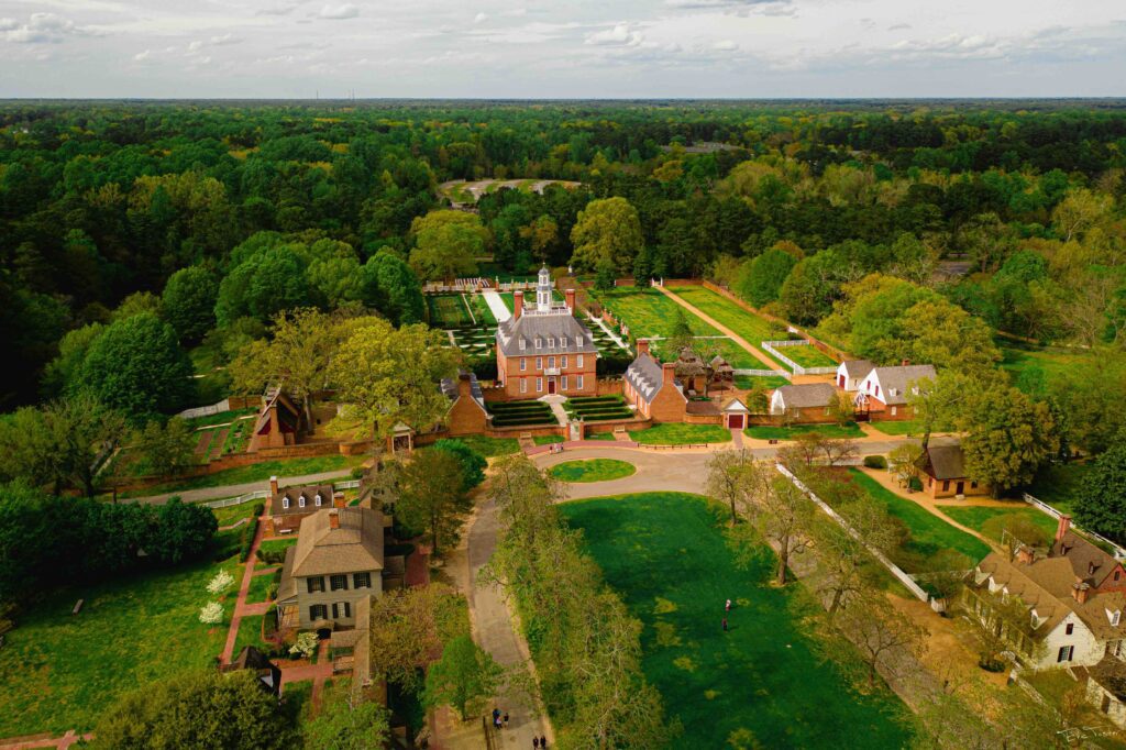 Aerial view of a large house in Williamsburg, VA. The surrounding area is largely greenery, with a couple of smaller houses nearby.