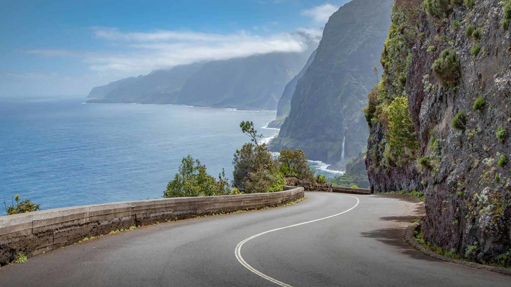 Curving coastal road with scenic ocean and mountain views, ideal for those seeking scenic drives in Portugal.