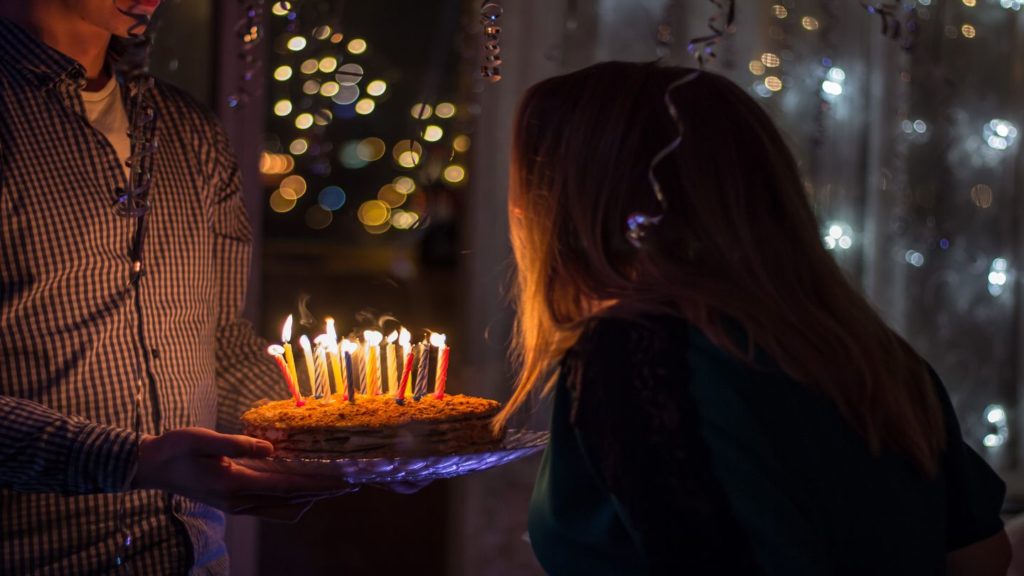 woman blowing out candles on birthday cake