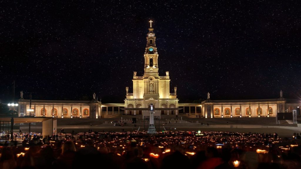 crowd of worshippers holding candles in the Sanctuary of Our Lady of Fátima Portugal