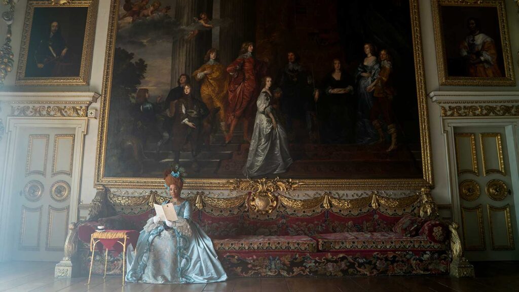 A person in an elaborate period costume inspired by Bridgerton series 2 standing in a historic room with ornate decorations and grand paintings.