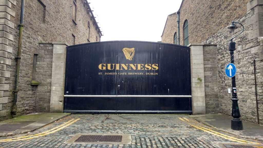 Entrance gate to the Guinness St. James's Gate Brewery in Dublin, steeped in the history of Guinness, with the brand's logo and cobblestone street.