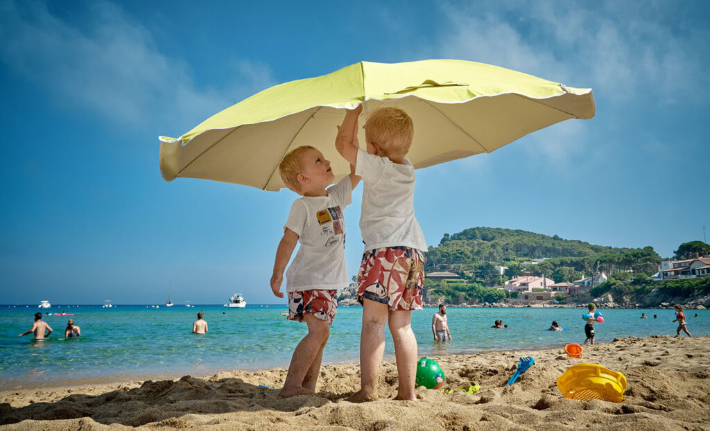 two boys putting up a beach umbrella