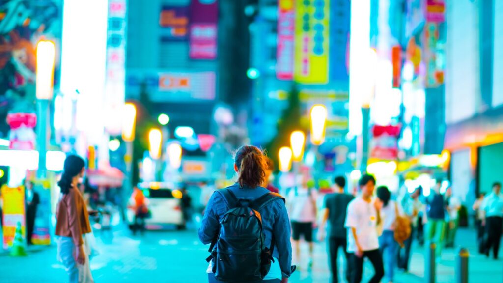 woman walking down a brightly lit street in tokyo