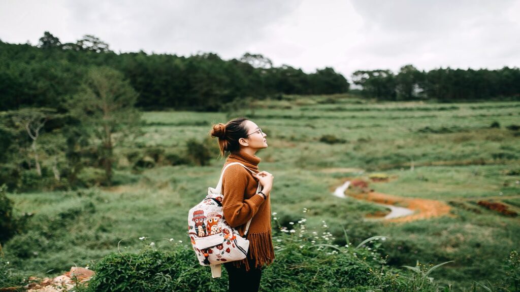 woman closing eyes and breathing while travelling in nature