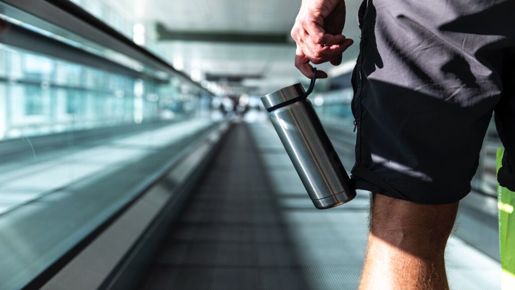 traveller using a reusable water bottle in airport
