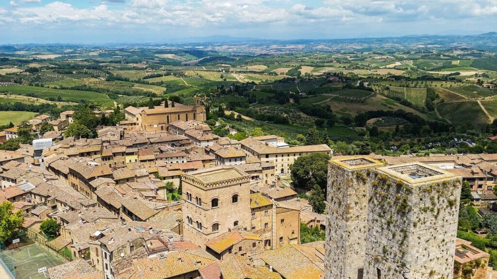 Hilltop view looking down at the roofs of San Gimignano with rolling green hills in the distance