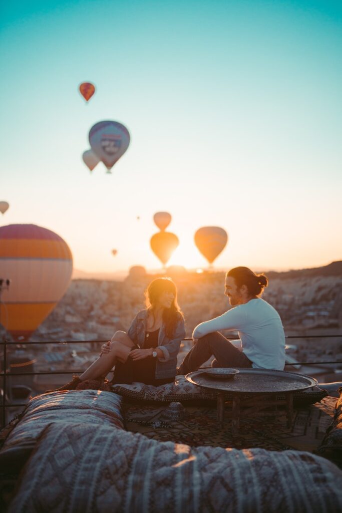 couple smiling at each in Cappadocia with hot air balloons at sunset in the background