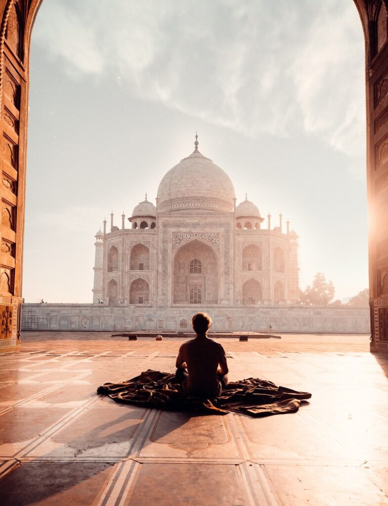 traveller sitting on a rug in front of the Taj Mahal at sunrise