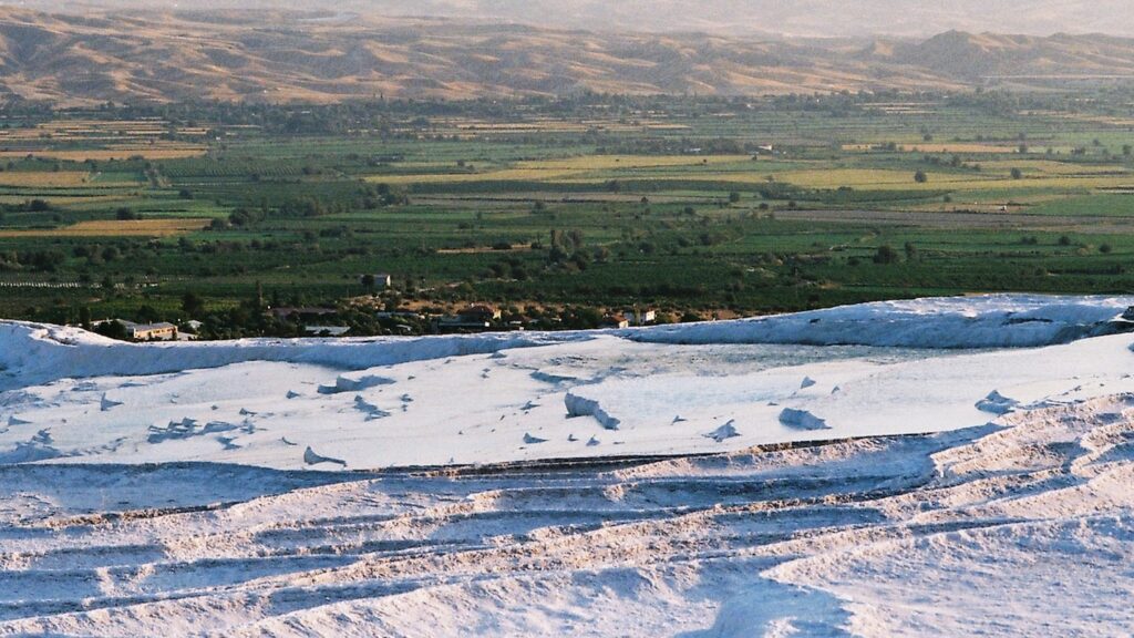 A view of Pamukkale's terraced pools, with a green landscape in the background