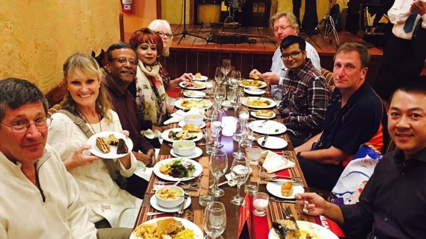 Image of Mita sitting at a long restaurant dining table with other Trafalgar guests