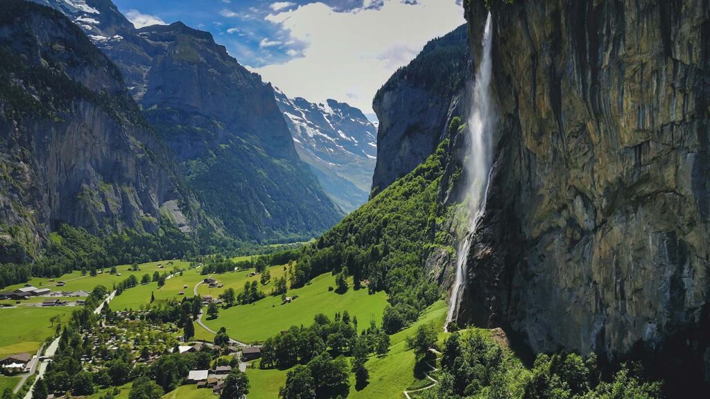 Image looking down a glacial valley in Switzerland, with Staubbach Falls tumbling into the frame on the right hand side