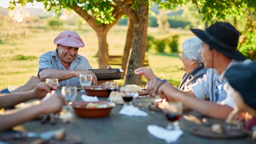 a group dining outside in Argentina, laughing. it's a sunny day
