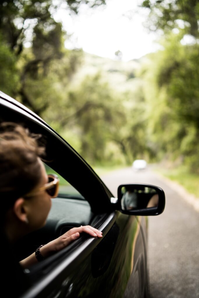 girl with sunglasses looking outside of window of car