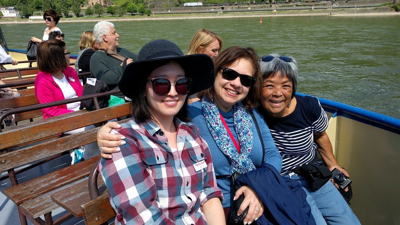 Three people posing for a photo on a boat, smiling with sunglasses on, enjoying the shared experiences of a Trafalgar tour