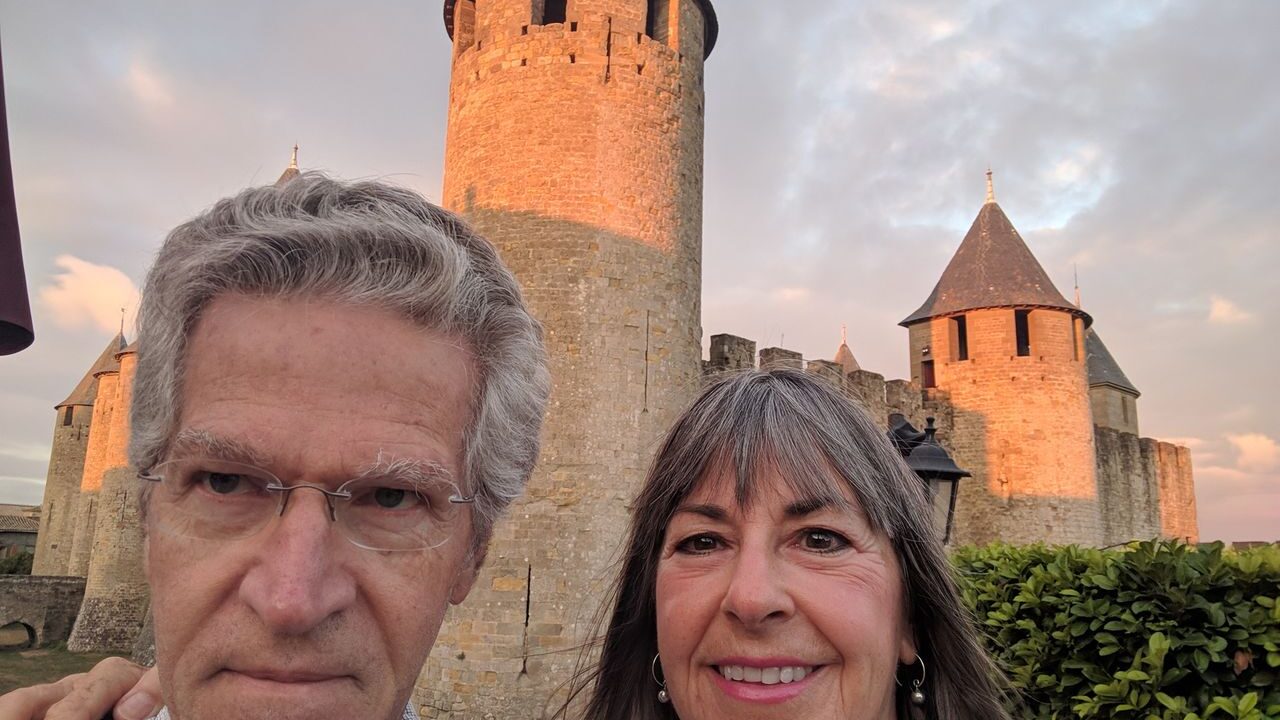A couple taking a selfie in front of Medieval fortifications in Carcassonne, France.