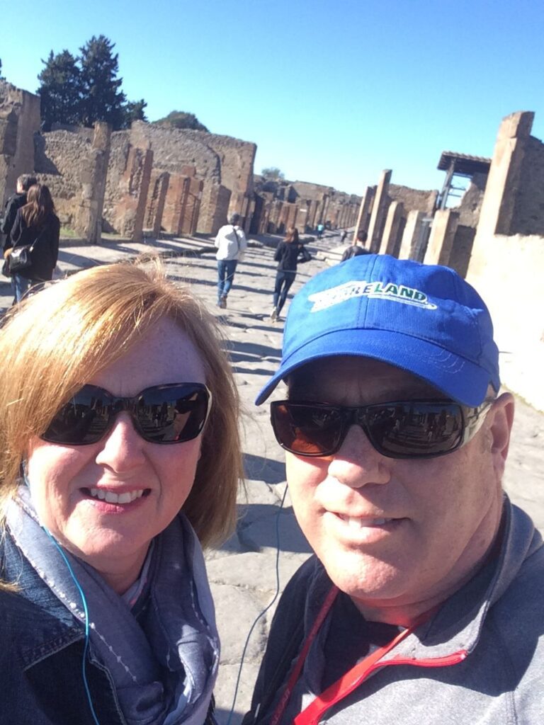 A couple smiling at the camera taking a selfie in Pompeii