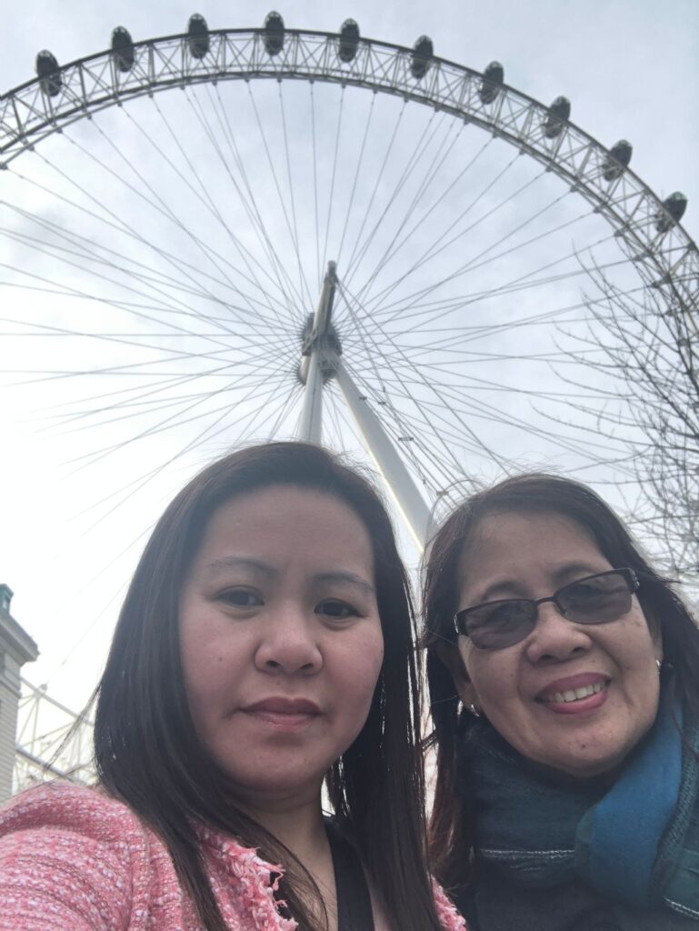 Mother and daughter smile for a selfie taken in front of the London Eye