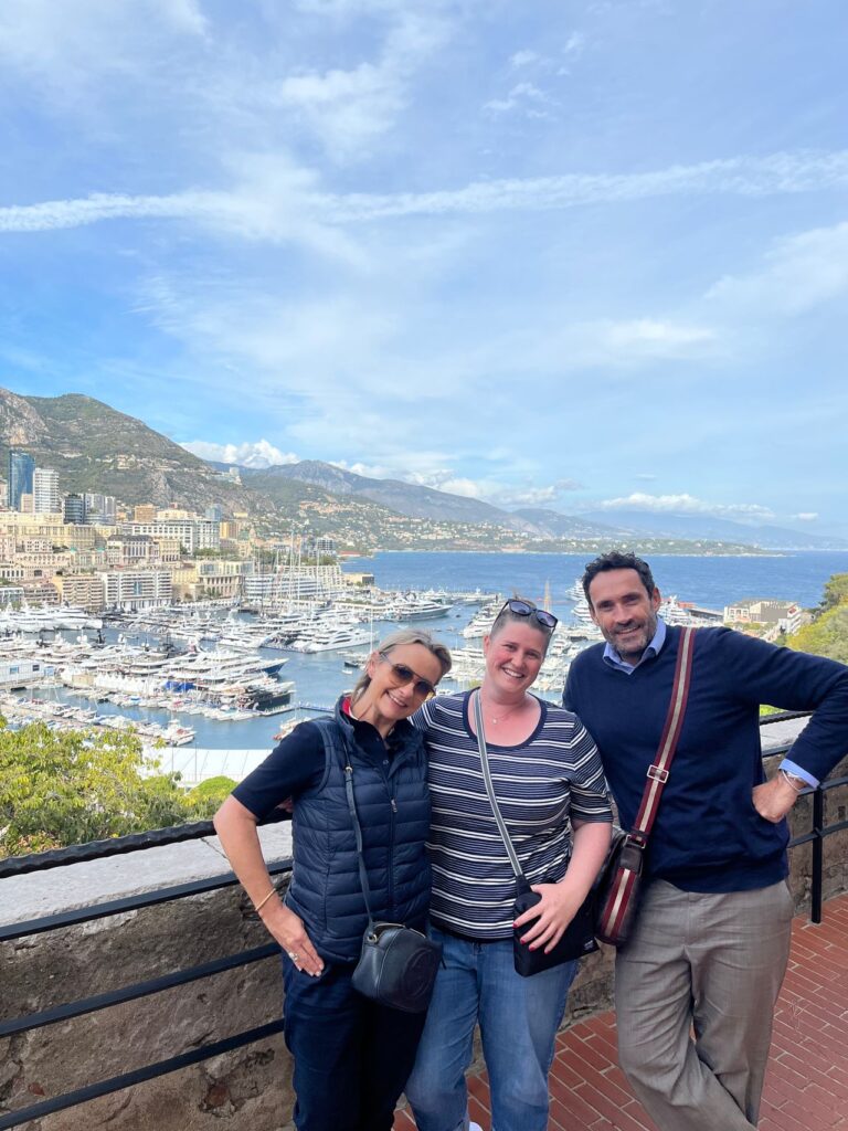 Two women and a man posing in front of a harbour and ocean landscapes