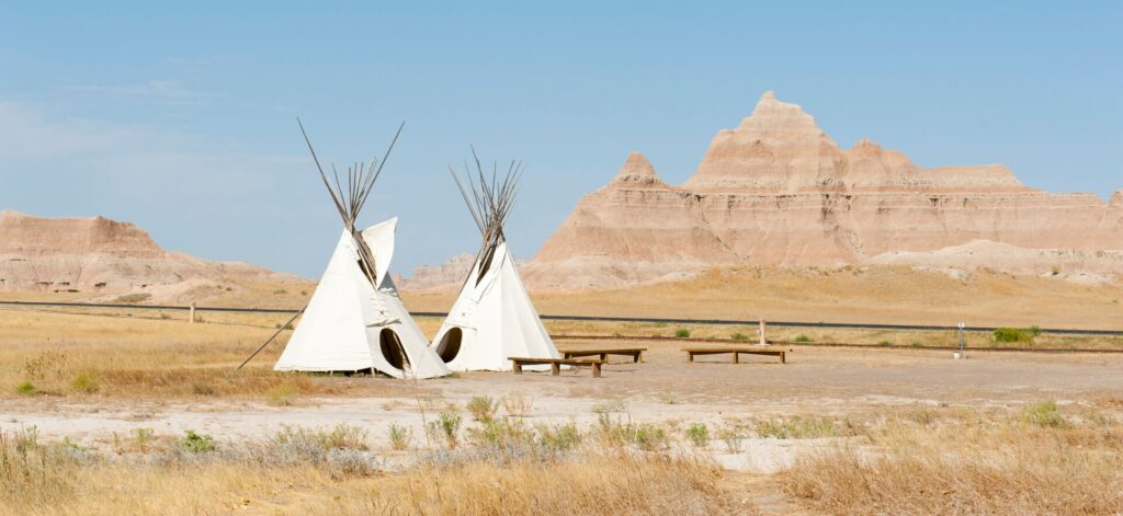 Teepee tents against the eroded landscape and grass prairies of Badlands National Park, South Dakota.