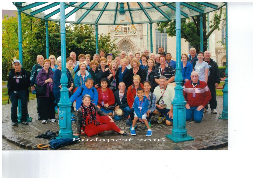 Group of tourists making friends while traveling, posing under a gazebo in Budapest, 2016, with the text "Budapest 2016" at the bottom.