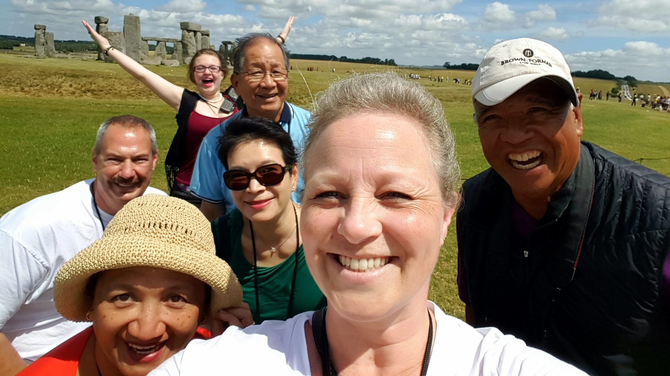 Making friends while traveling in front of Stone Henge. A group of new friends who met on their Trafalgar Tour pose for a selfie with Stone Henge in the background