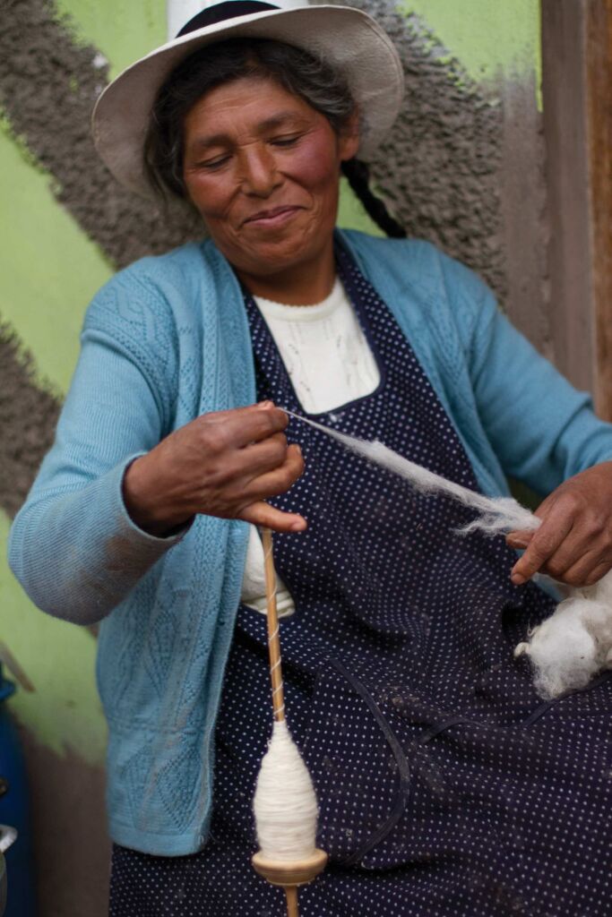 Quechua woman weaving fabric and smiling