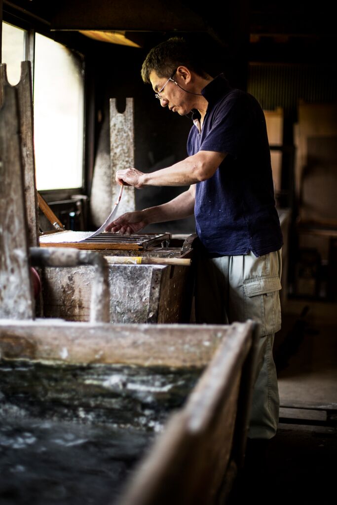 Man standing over washi paper in a workship