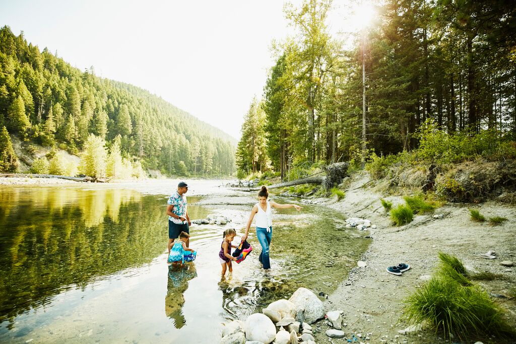 Mother and Father playing with daughters in river on summer afternoon
