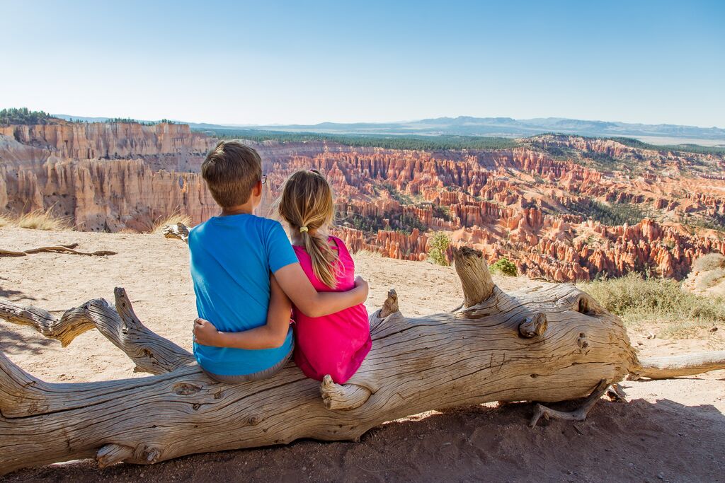 Brother and sister sitting on log, Bryce Canyon, USA