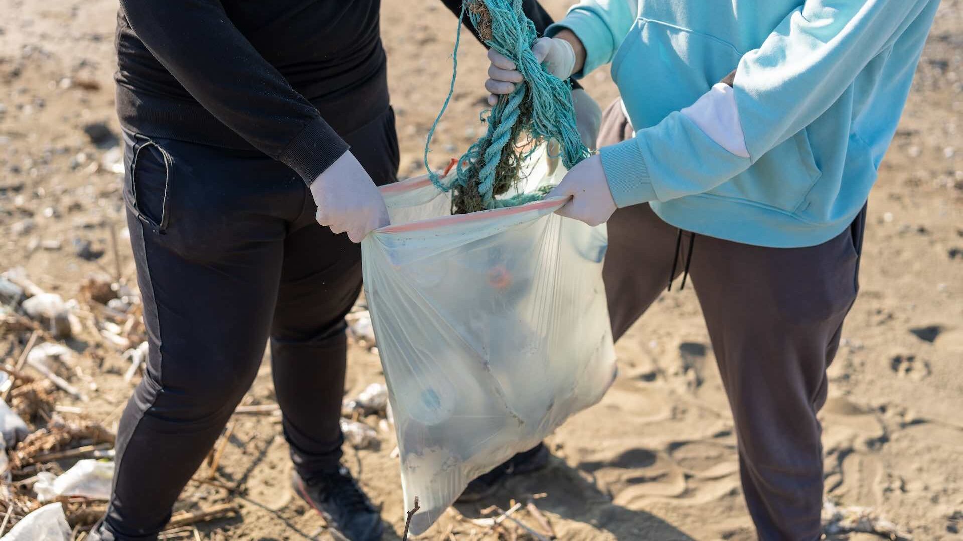 Close up of putting rubbish in bag on beach