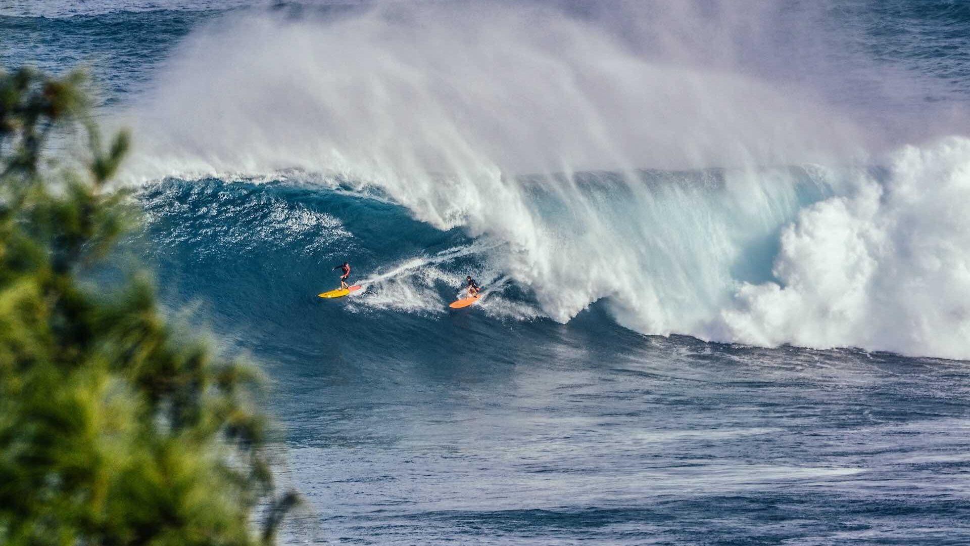 Surfers riding wave on Jaws surf break, Hawaii
