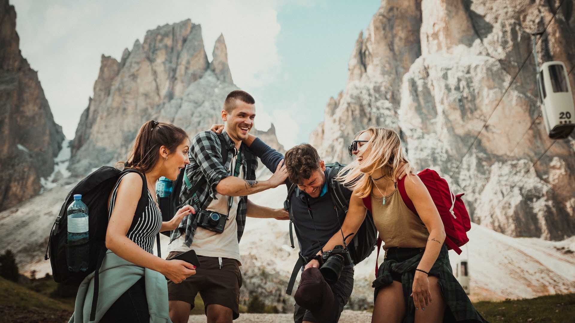 Two women and two men travellers laughing with mountains in background