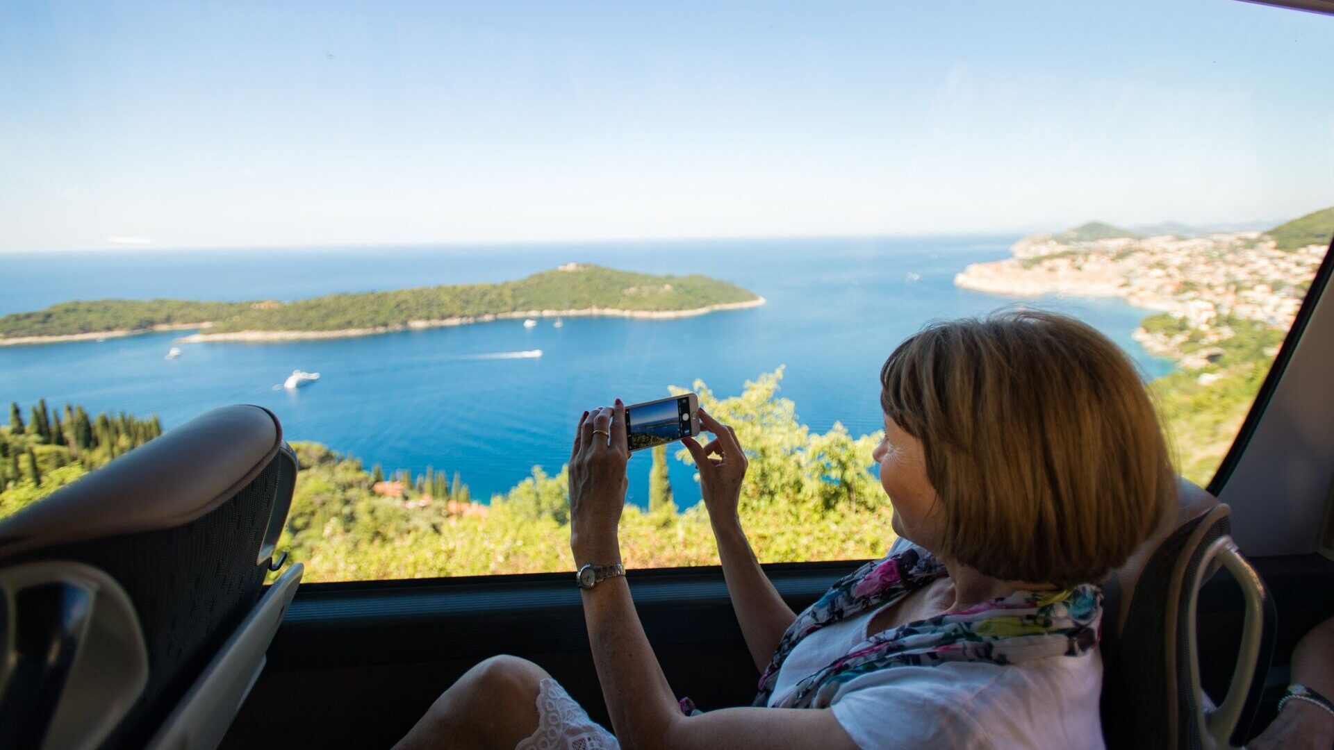 Woman taking photograph out of large coach window