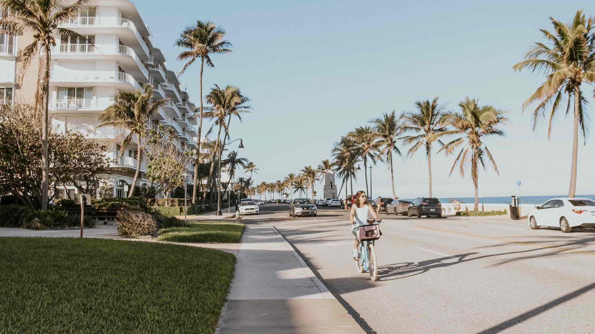 Woman cycling along coastal road, palm beach, USA