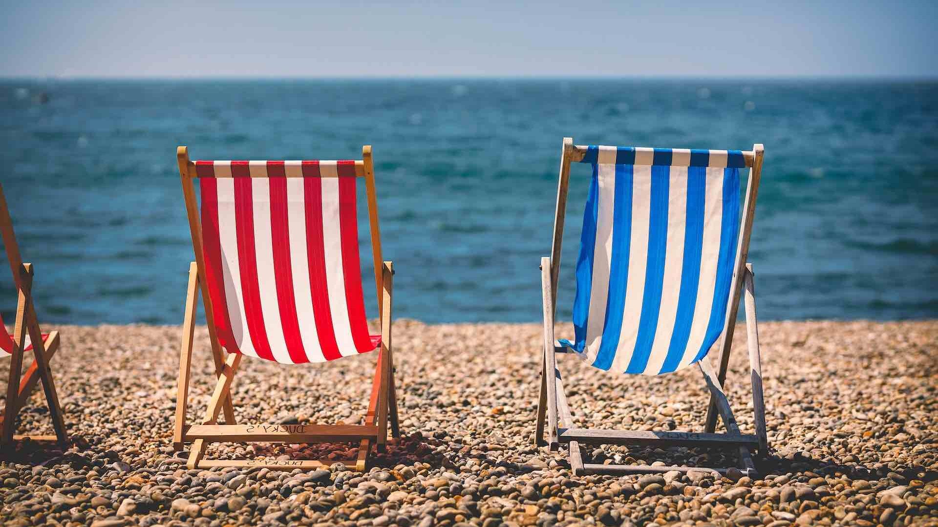 Blue and red deck chairs on pebble beach