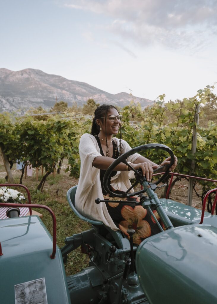 Avery laughing while driving a farming vehicle while in what looks like a vineyard - just another fun experience when you travel with Trafalgar.