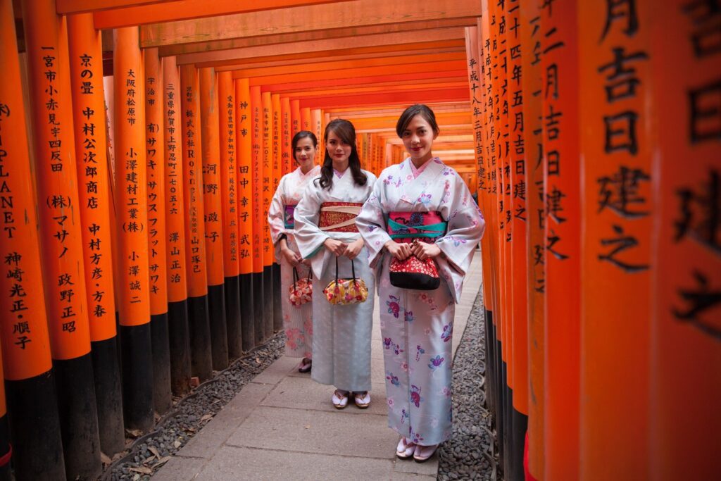 women wearing kimonos and standing under torii gates in Japan