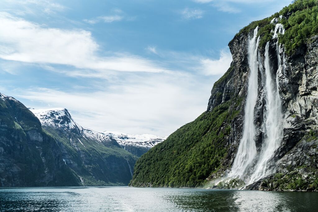 A huge waterfall falls down into a river below, the epic beauty of the fjords make the perfect wellness holiday